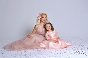 Romantic portrait session with pink dress and scattered rose petals on white floor.