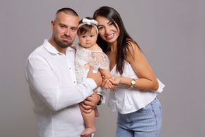 Family portrait session with coordinated white and denim outfits against grey backdrop.