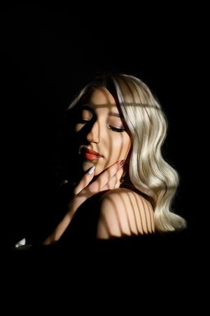 Dramatic black and white portrait with shadows and light creating artistic effect.