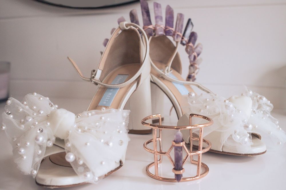 Elegant white pearl-adorned bridal shoes paired with hair accessories and a rose gold jewelry display stand.