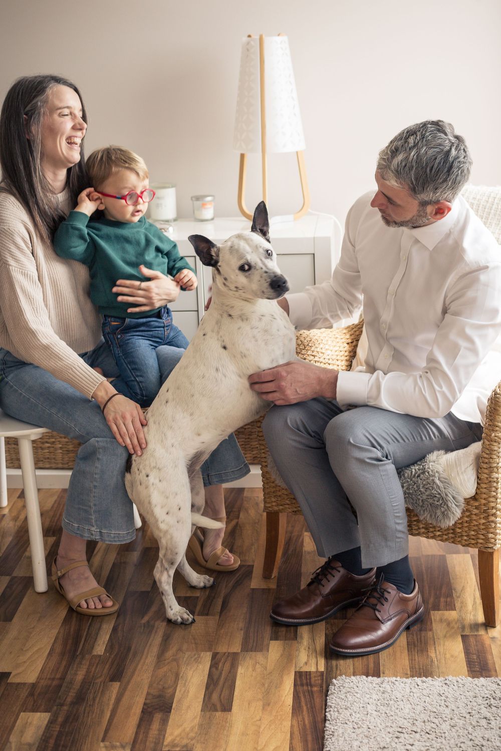 A sweet series of photos showing a dog cuddling and playing with people on a wooden floor.