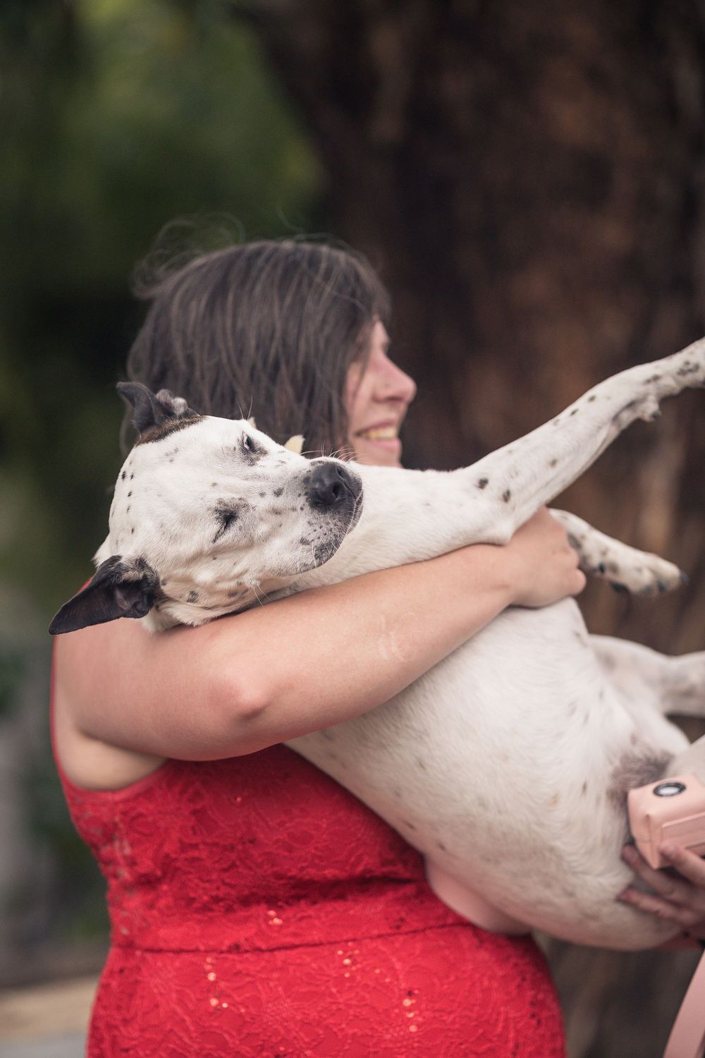 A series of images showing a white dog hugging and resting their head on a person wearing a red shirt.