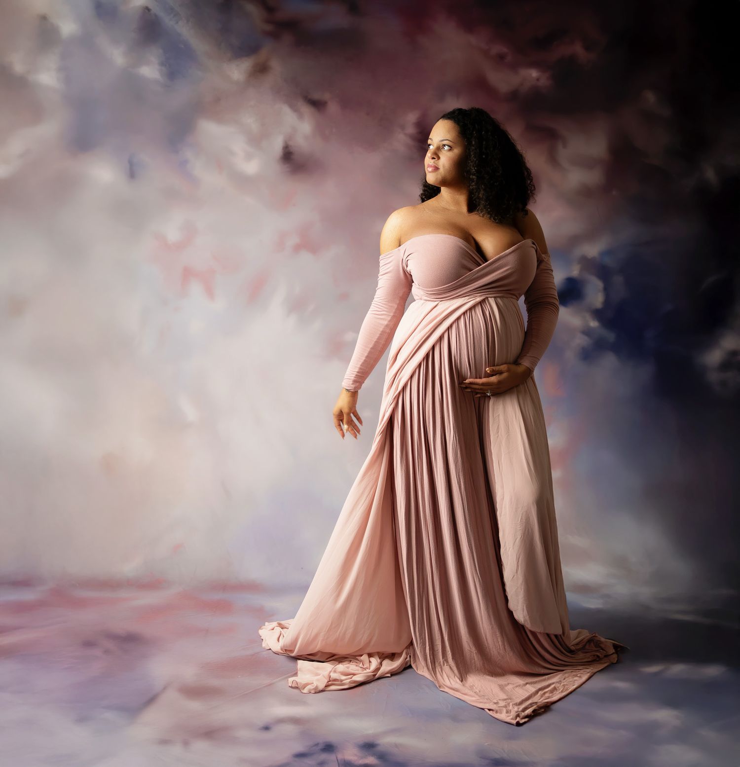 Four artistic black and white maternity photos show an expectant person in various poses wearing black clothing against a light backdrop.