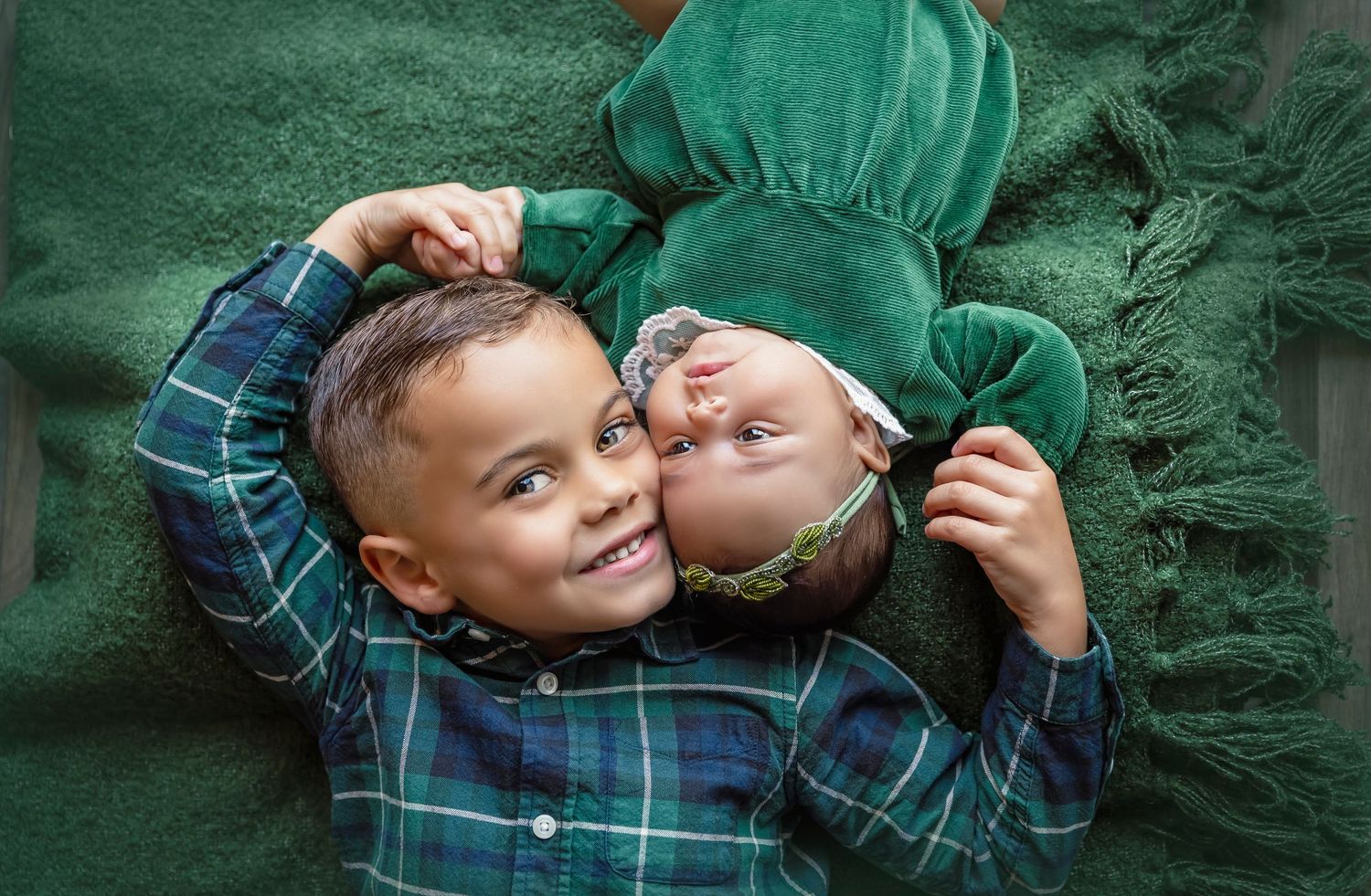 siblings laying on the floor pose side by side looking at the camera