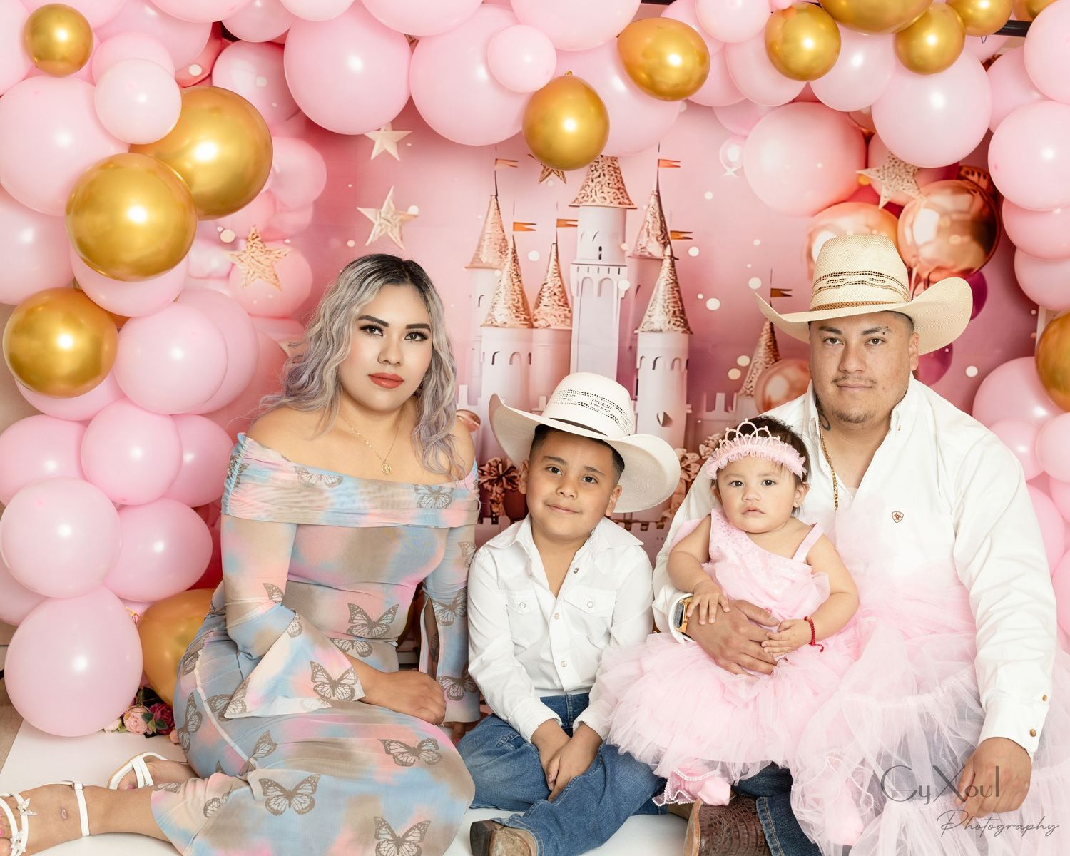 Disney princess themed birthday party setup with pink balloon arch, gold accents and castle backdrop decorations.