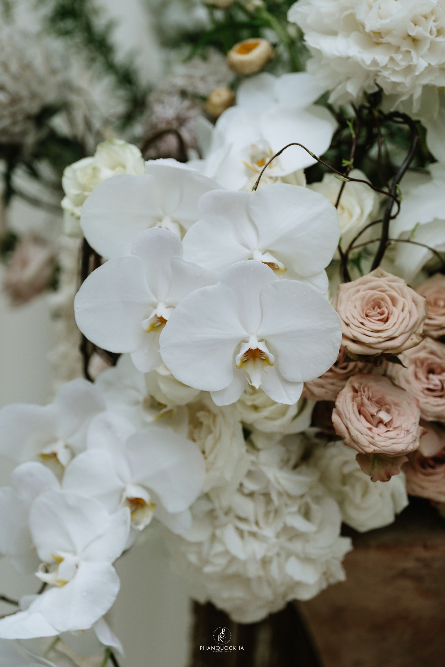Close-up of elegant wedding floral arrangement featuring white orchids and blush pink roses.