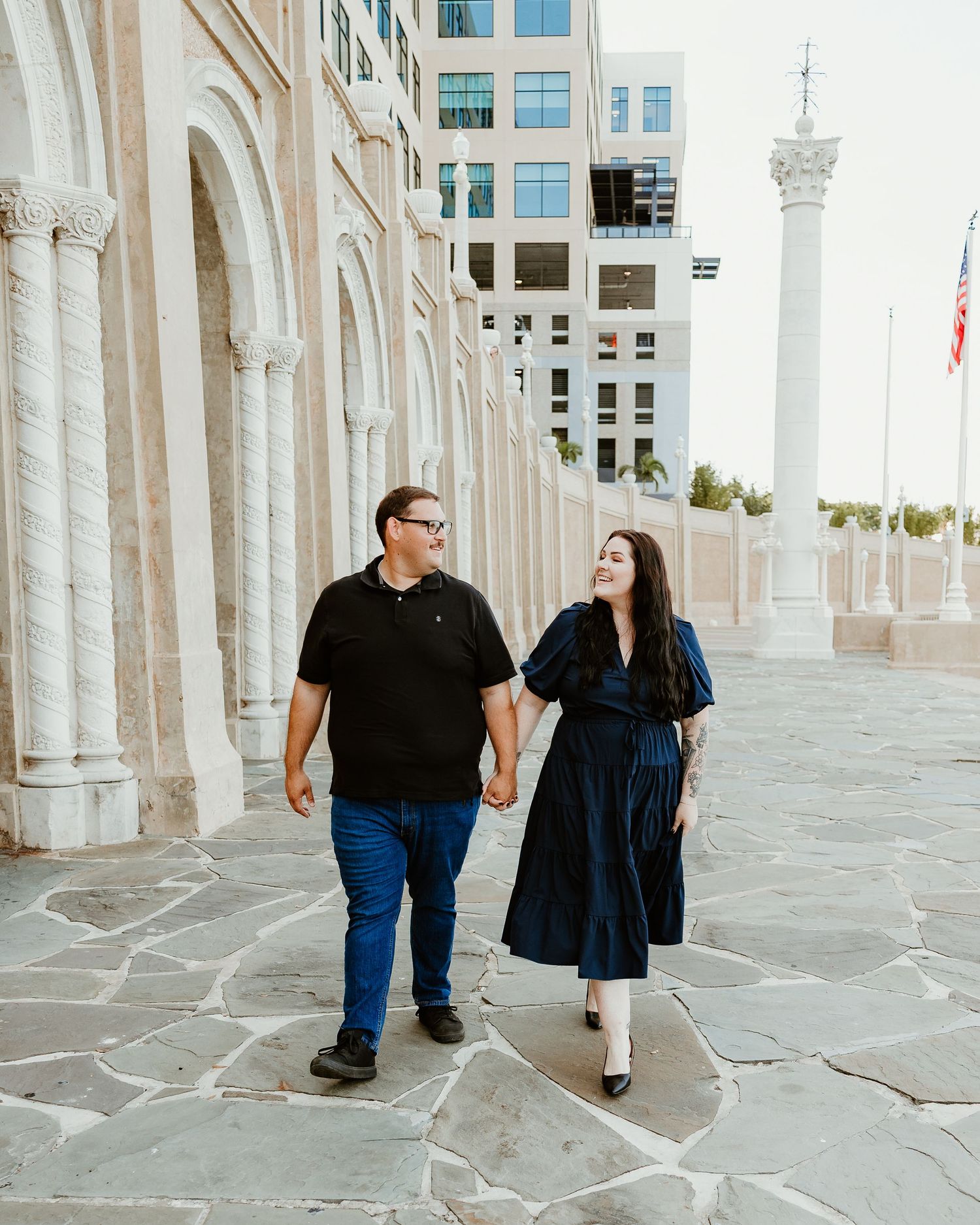 A couple walks together through elegant white marble columns at a grand historic building.