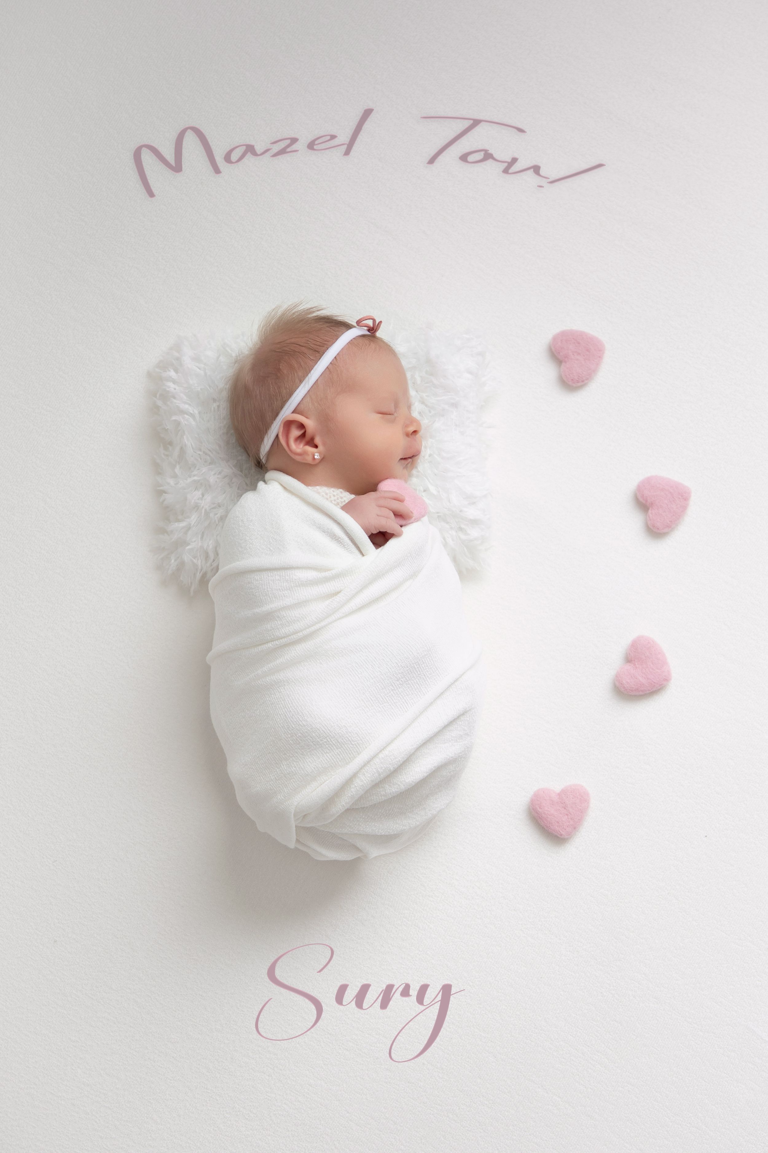 Newborn baby wrapped in white swaddle with pink heart decorations and Mazel Tov text on white background.