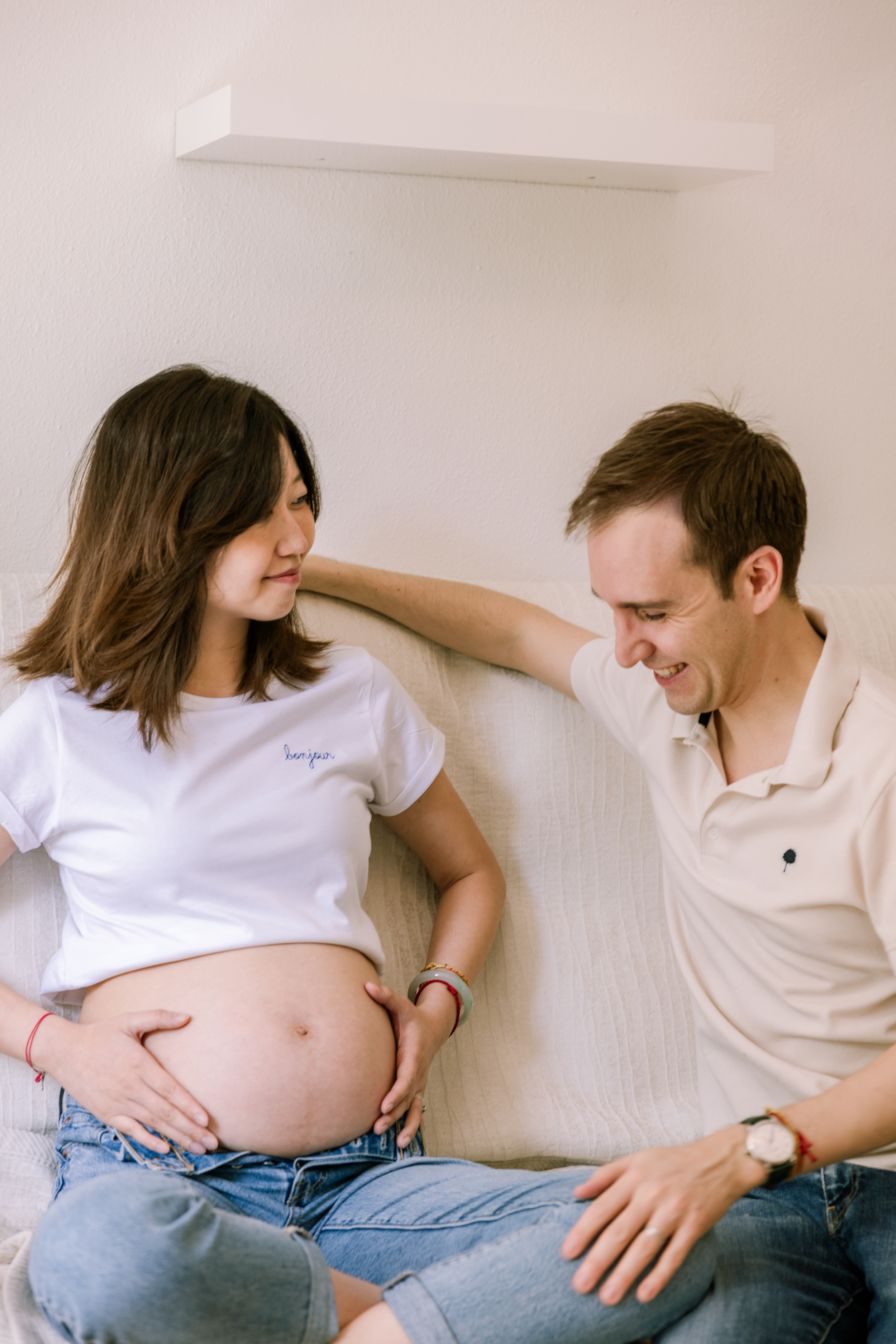 Couple shares joyful moment during indoor maternity photoshoot.