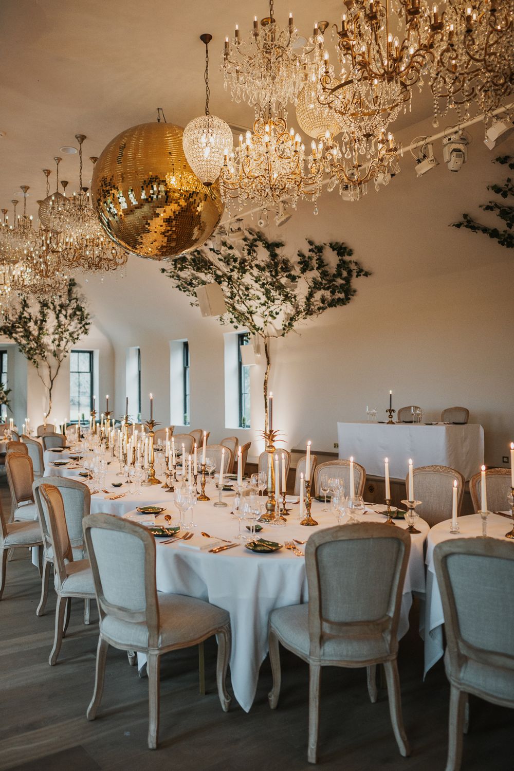 Elegant wedding reception tables set with white linens and crystal chandeliers in an upscale venue.