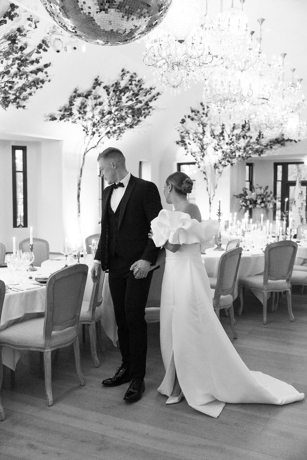 Black and white photo of a wedding couple during a private moment in an elegantly decorated reception room.