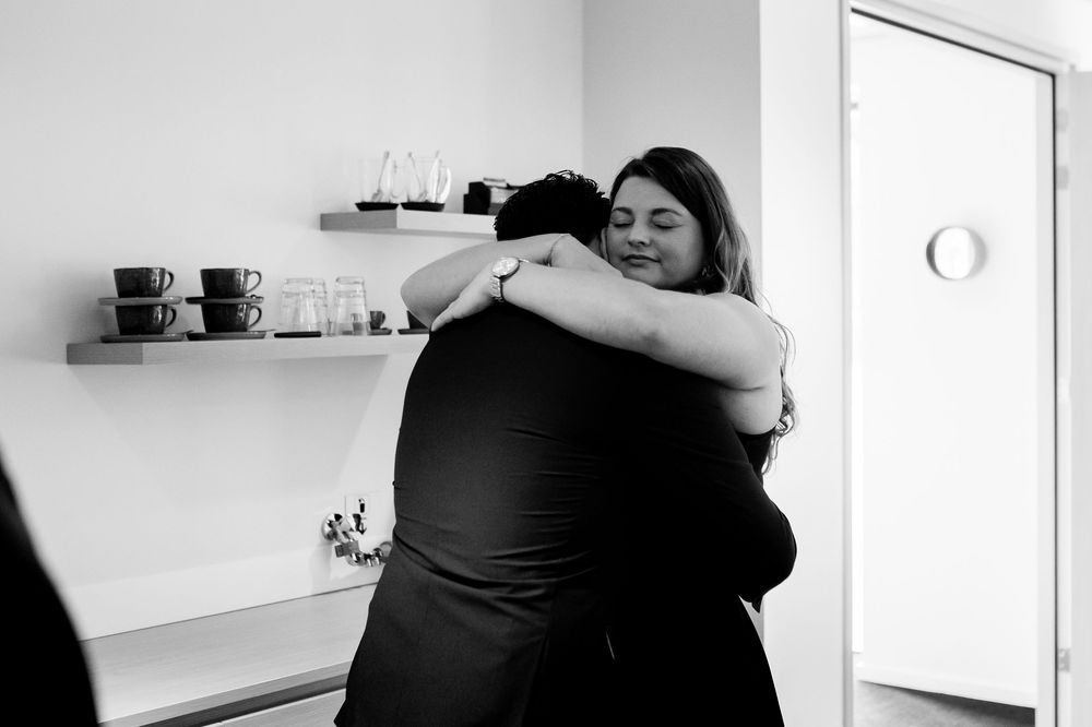Two people sharing a warm embrace in a minimalist black and white interior setting.