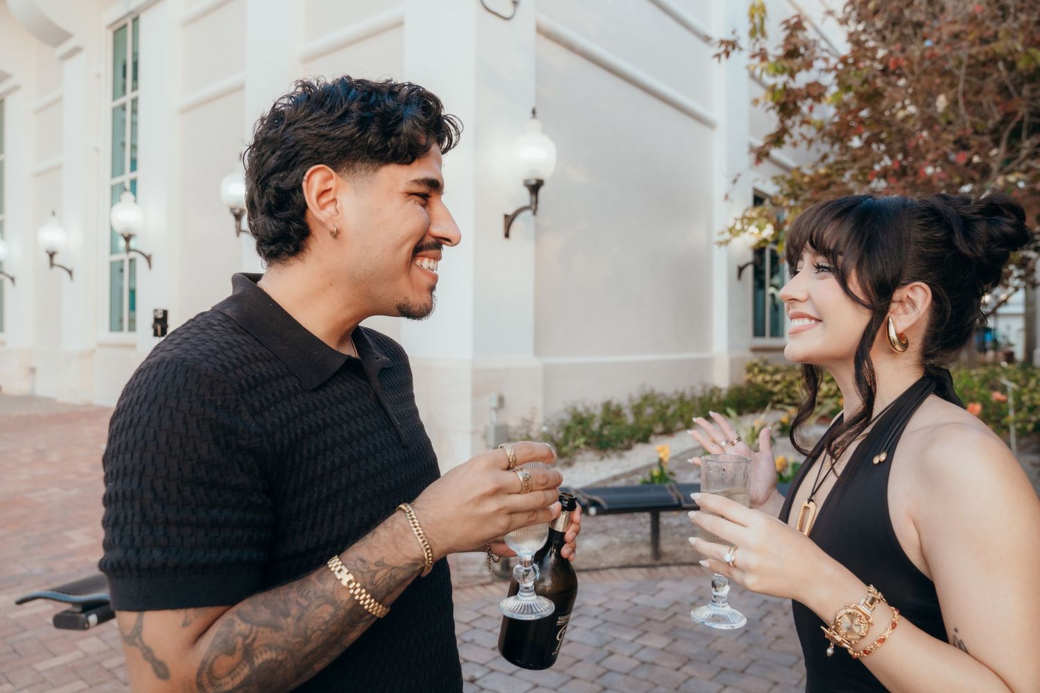 A man and woman smiling and toasting with drinks at an outdoor social gathering.