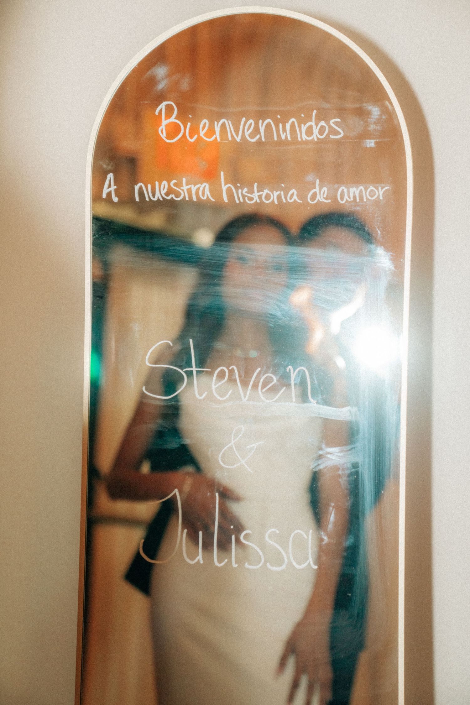 Wedding mirror sign reading Bienvenidos A nuestra historia de amor for Steven and Julissa with couple reflection.