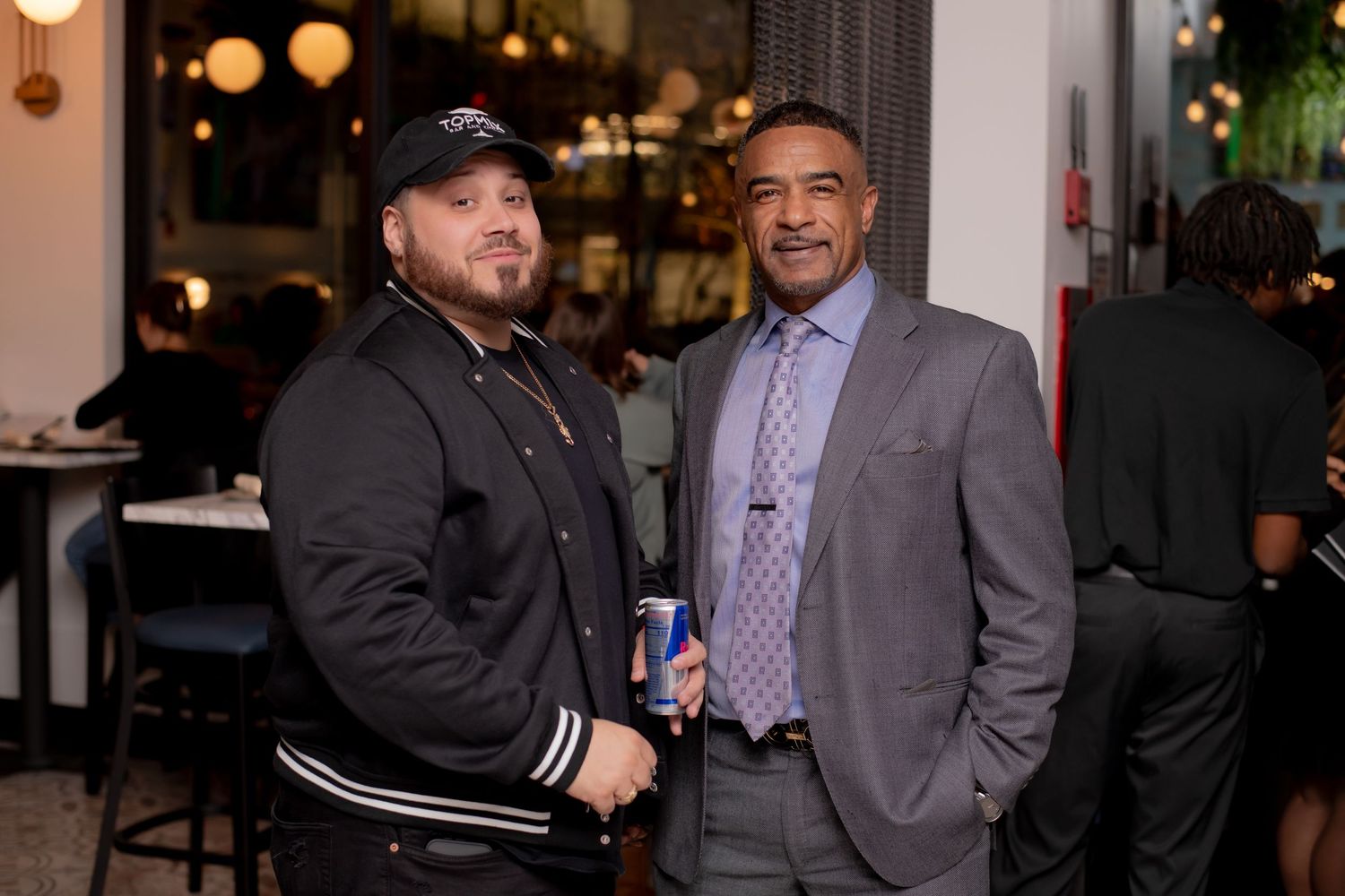 Two men pose together smiling at a restaurant social event.