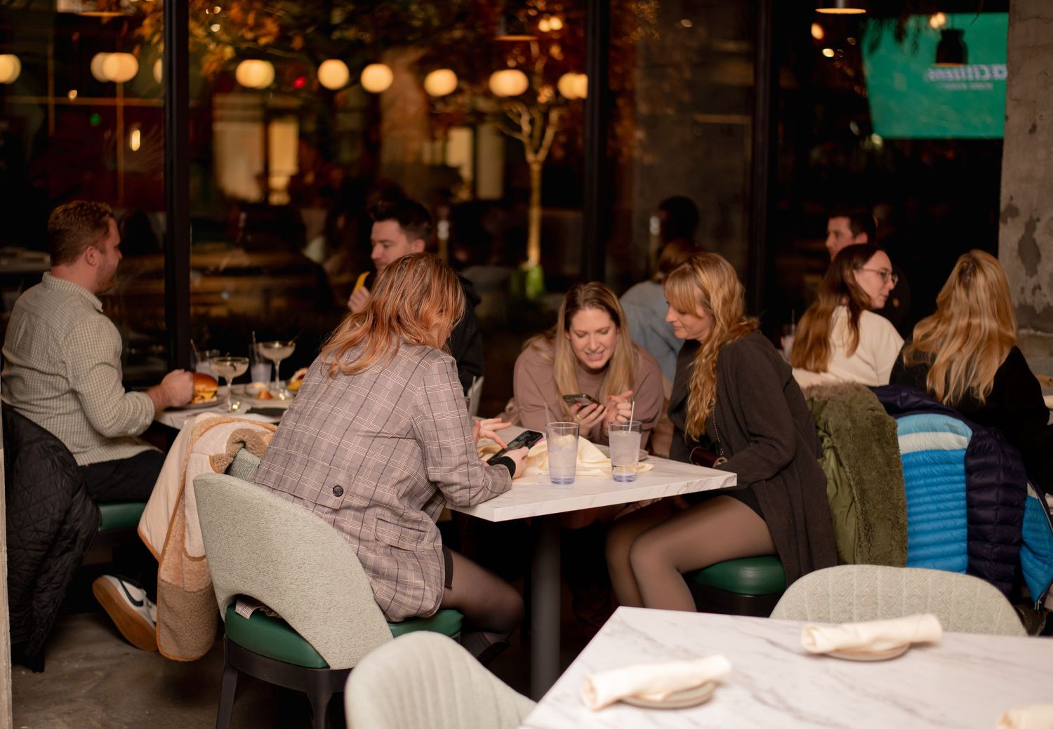 A group of diners enjoy an evening meal at a modern restaurant patio.