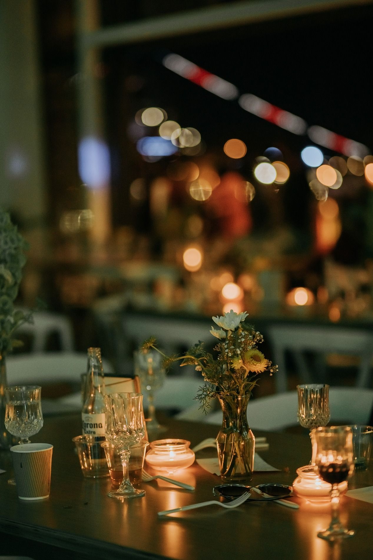 Elegant candlelit wedding reception table with floral centerpieces, crystal glassware, and bokeh lights in the background at The Lane.