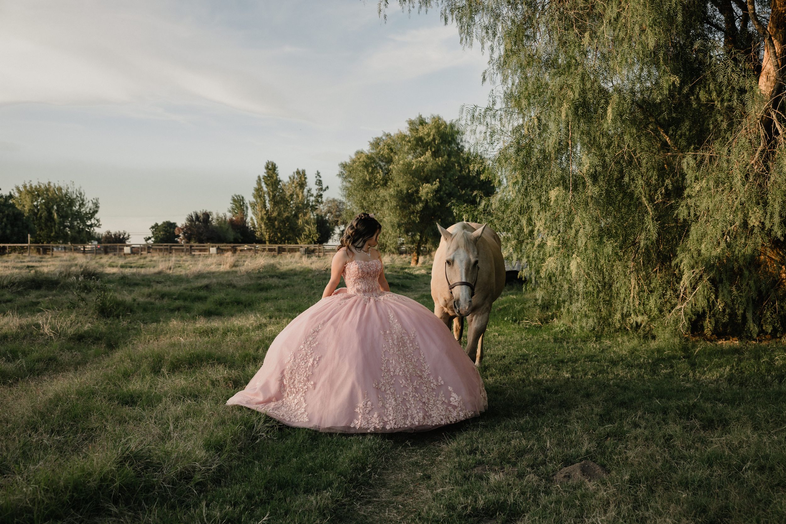 Bride in ballgown poses on lush lawn before a stunning white castle venue with Gothic arched windows and gold doors.