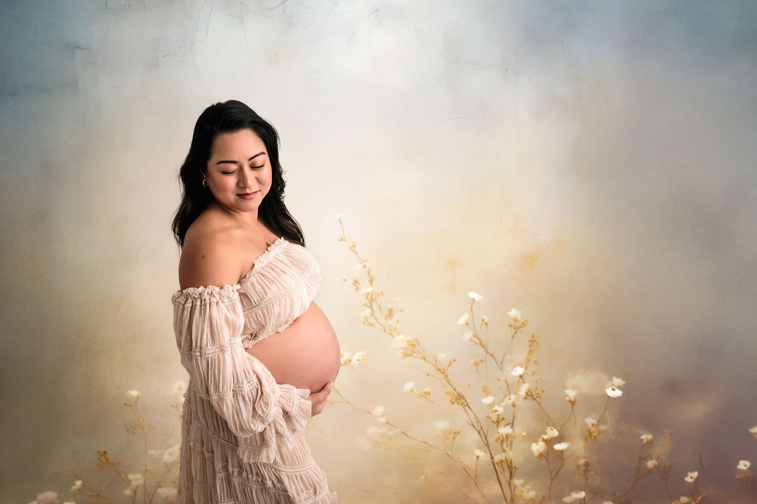 Smiling pregnant woman in white lace off-shoulder gown cradling her baby bump among painted wildflowers on a dreamy digital backdrop.