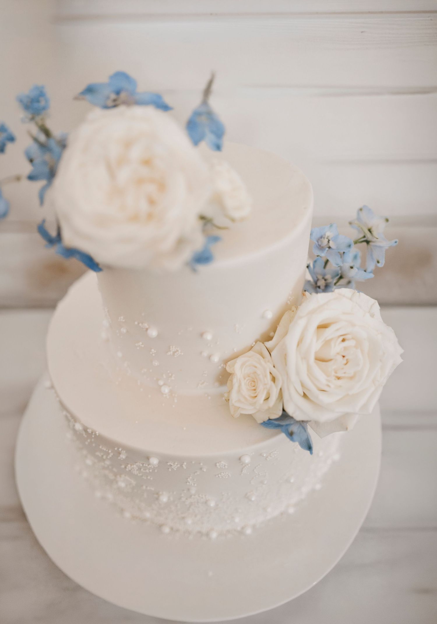 ivory pearl cake with blue flowers and white roses