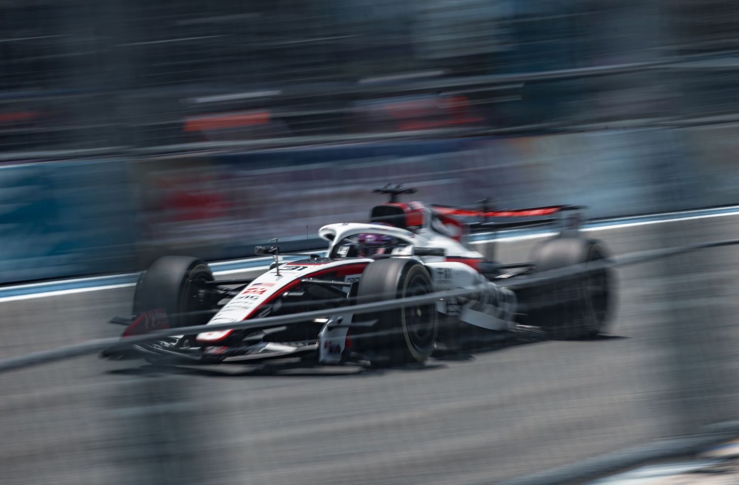 A Formula 1 race car speeds through a street circuit, captured with motion blur emphasizing its high velocity.