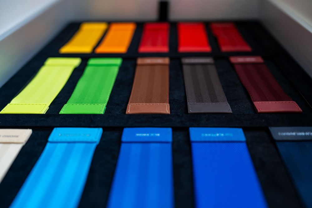 Colorful automotive paint sample swatches displayed in rows on a black velvet tray in a car showroom.