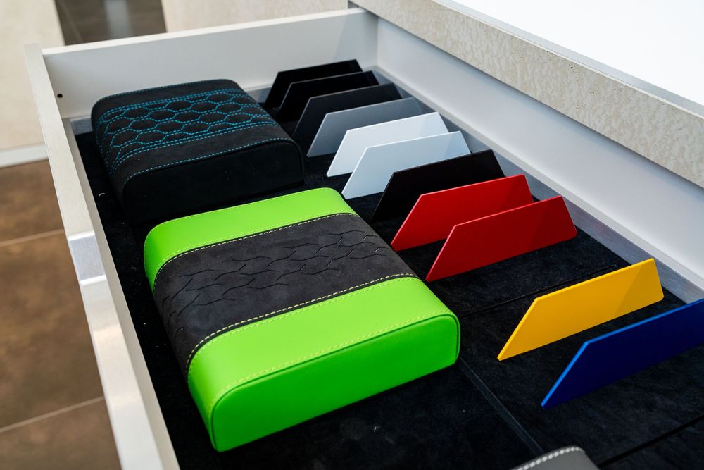 An open drawer displaying Lamborghini interior upholstery and color samples including green, black, red, and grey options.