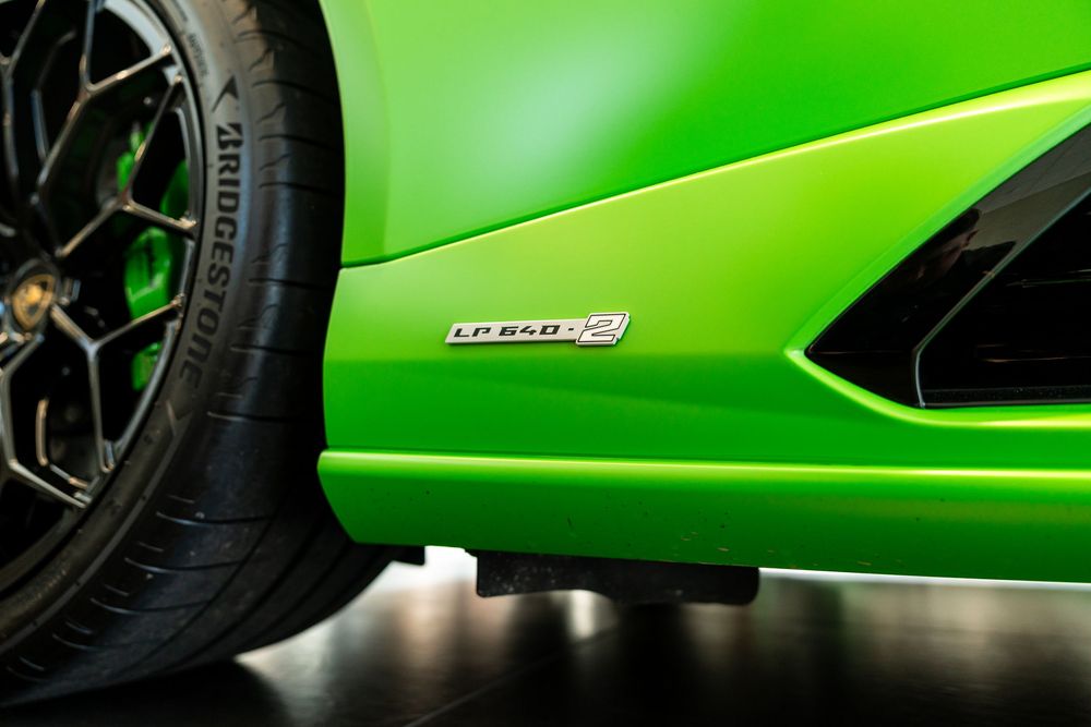 Close-up of a green Lamborghini Huracan LP 640-4 badge on the side panel with Bridgestone tire visible.