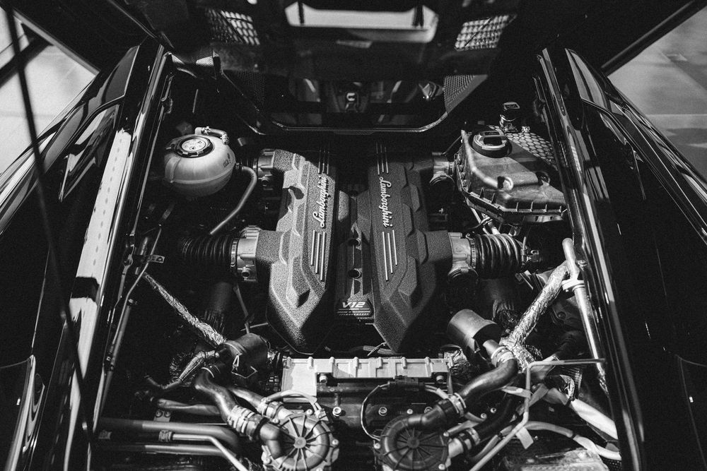 Black and white close-up of a high-performance car engine bay showcasing intricate mechanical components.