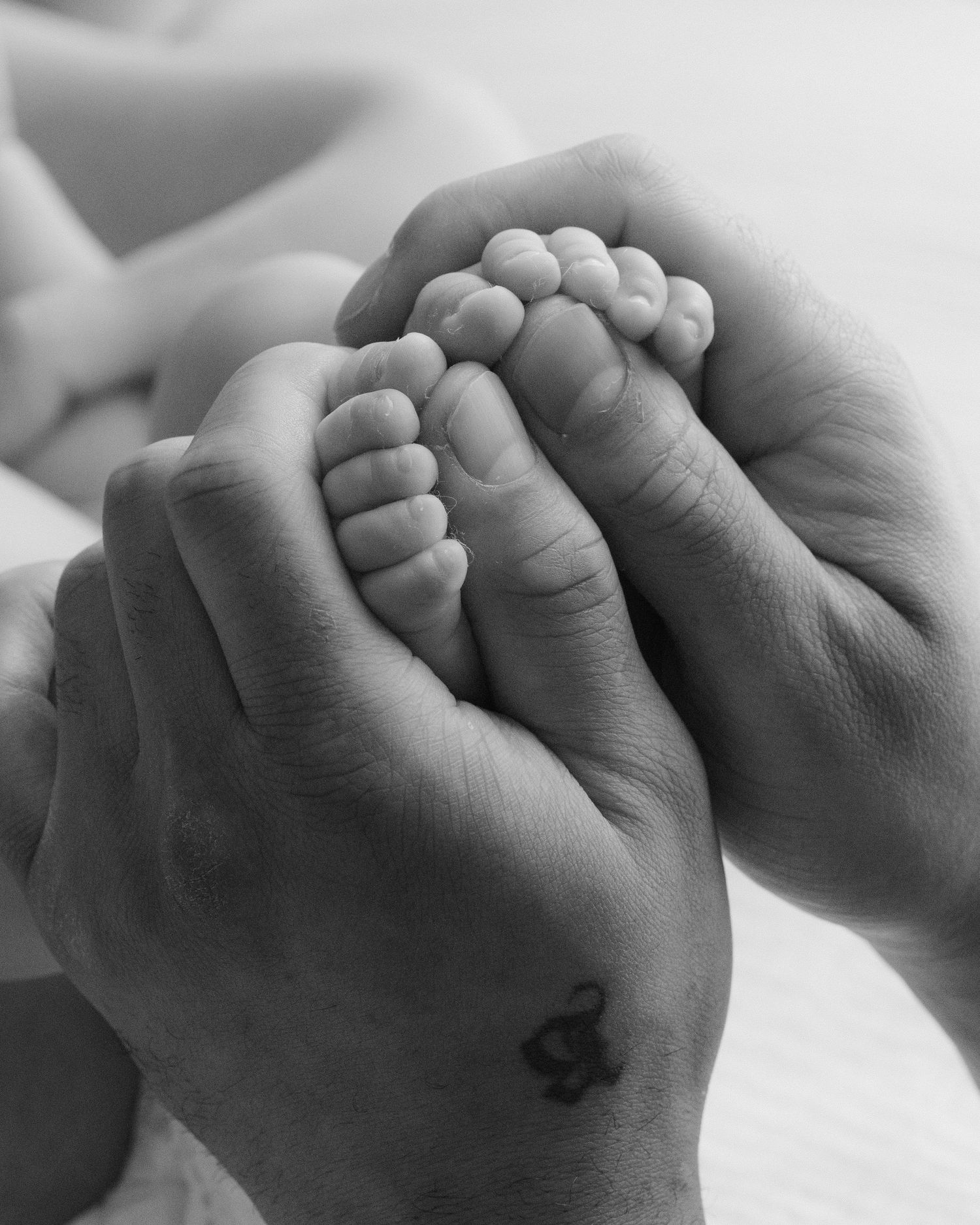 Close up detail image of dad’s hands holding newborn baby’s little toes at in-house,e photo session in Vancouver