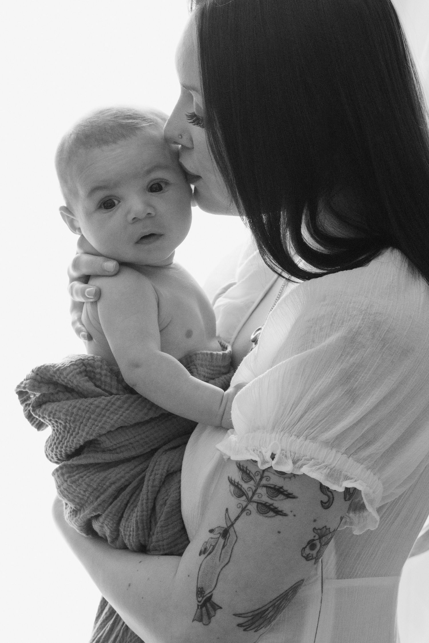 Mother kissing newborn baby’s head in black and white, lifestyle newborn photography North Vancouver