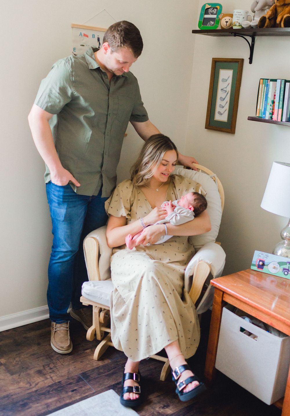 New parents admire their newborn baby in a cozy nursery rocking chair.