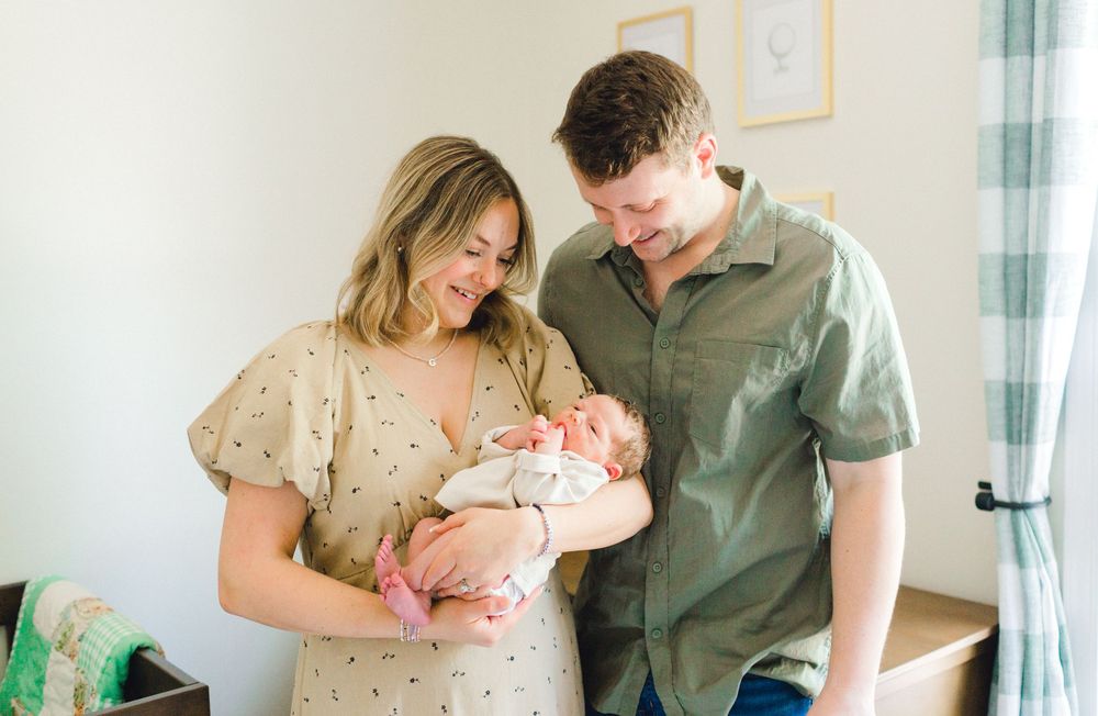 Happy couple gazing lovingly at their newborn baby in a bright nursery room.