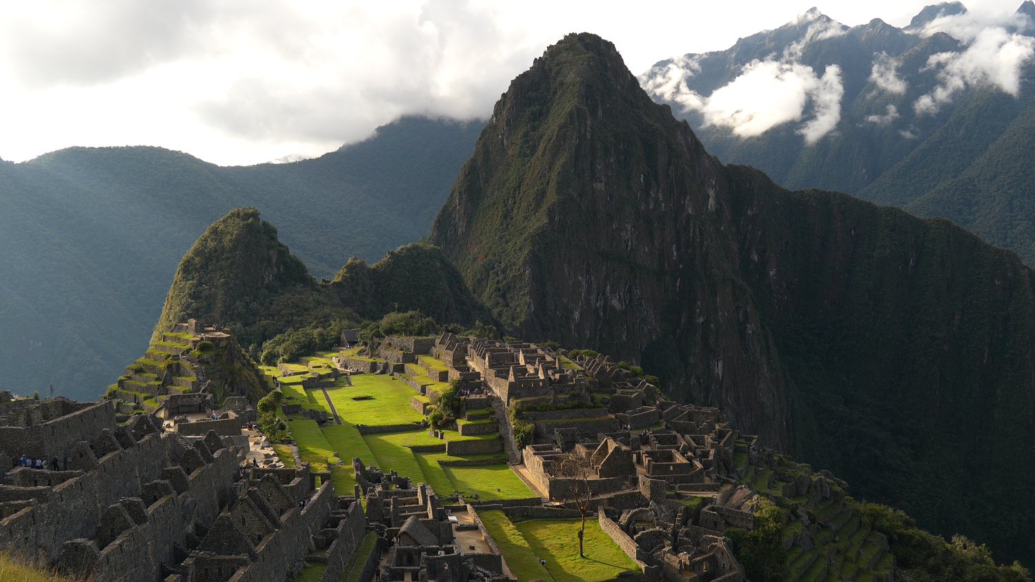 Aerial panoramic view of ancient Machu Picchu Inca citadel ruins surrounded by misty Andean mountains.