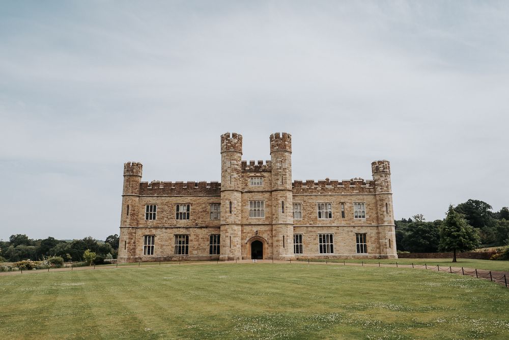 Historic Leeds Castle in Kent, England, with medieval stone towers and battlements set against a lush green lawn.