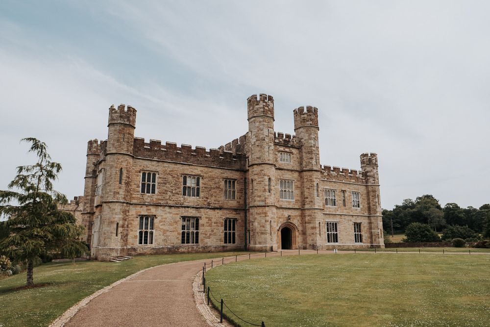 Historic Leeds Castle with battlements and turrets surrounded by lush green lawns in England.