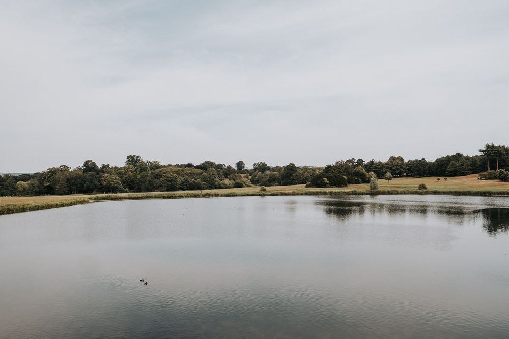 Serene lake reflecting green trees and cloudy sky in a peaceful countryside landscape.