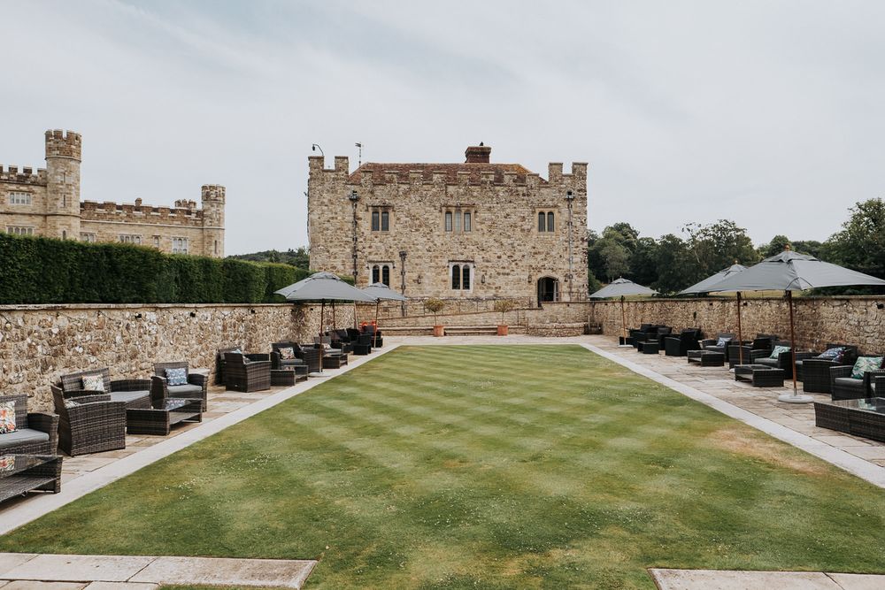Elegant castle courtyard with manicured lawn, outdoor seating, and stone walls in England.
