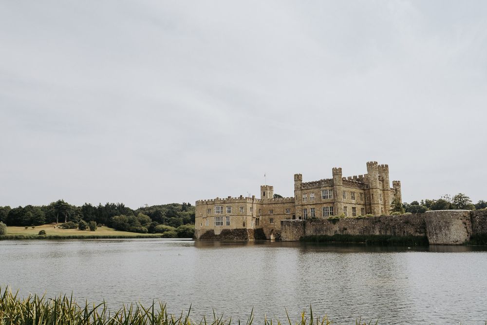 Leeds Castle surrounded by a moat on a cloudy day in Kent, England.
