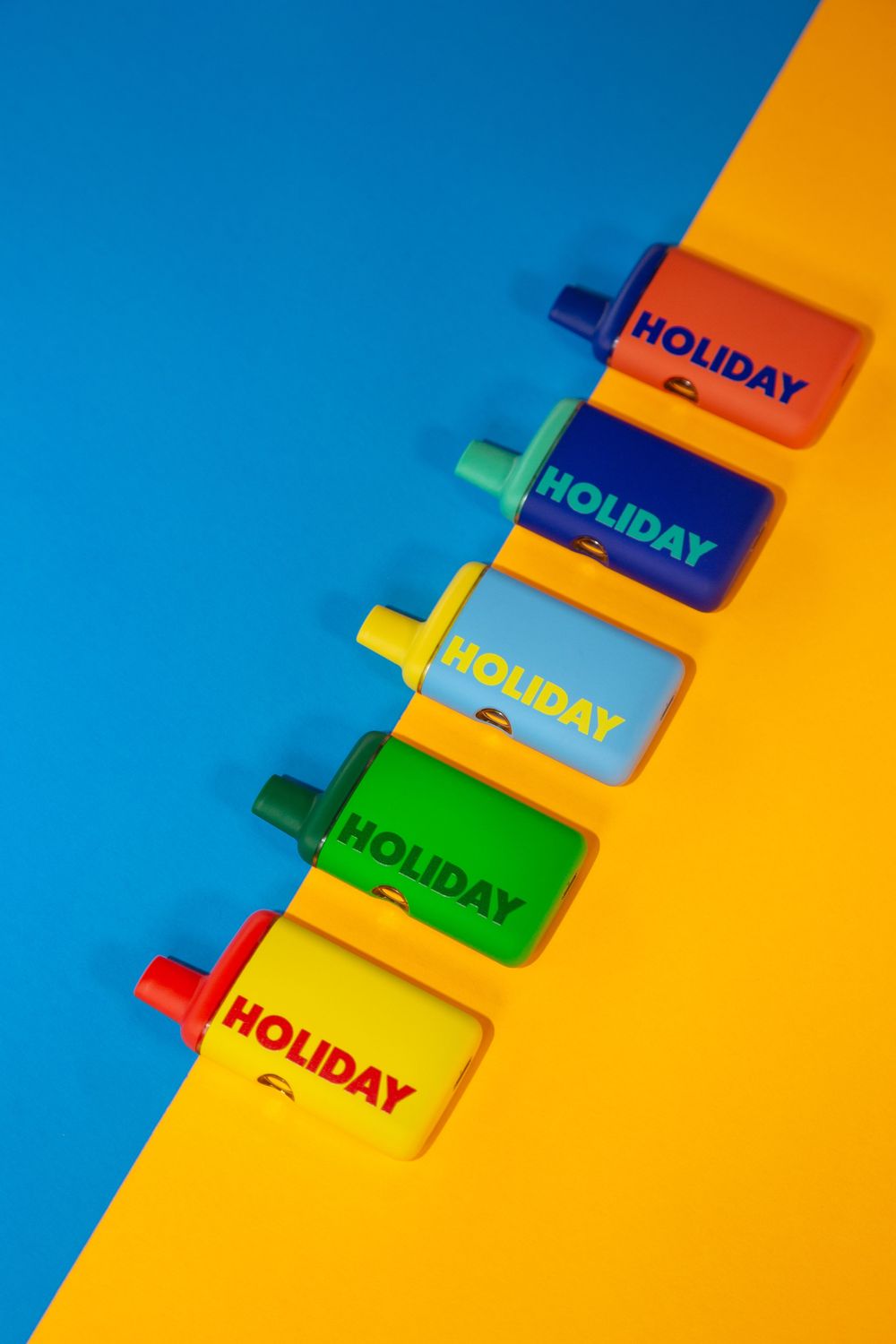 Colorful holiday-labeled bottles arranged diagonally on a vibrant blue and orange background.