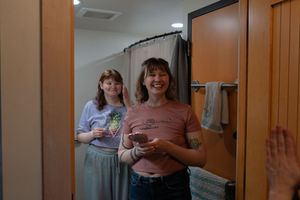 Two women smiling and laughing together in a bathroom doorway.