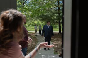 Guest arriving at outdoor wedding venue viewed through doorway on sunny day.