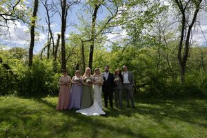 Wedding party group portrait with bride, groom, bridesmaids and groomsmen in green forest.