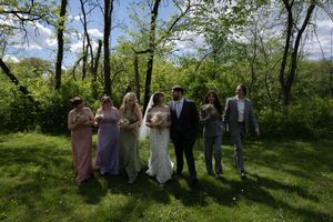Wedding party walks together across green lawn with bridesmaids in pastel gowns and groomsmen in gray suits.