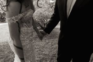 Black and white close-up of bride and groom holding hands in romantic wedding portrait.