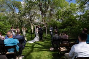 Bride and groom sharing a kiss under a floral arch during an outdoor garden wedding ceremony.