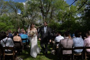 Newlyweds walk back down aisle hand in hand after outdoor garden wedding ceremony.