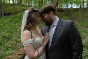 Bride and groom sharing intimate forehead touch moment in lush green forest wedding portrait.