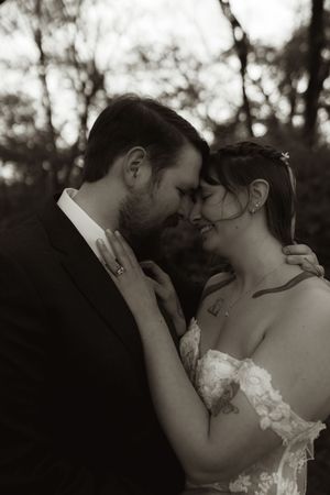 Black and white portrait of bride and groom touching foreheads tenderly in a romantic embrace.
