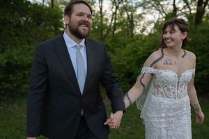 Newlywed couple holding hands and smiling while walking outdoors after their wedding ceremony.